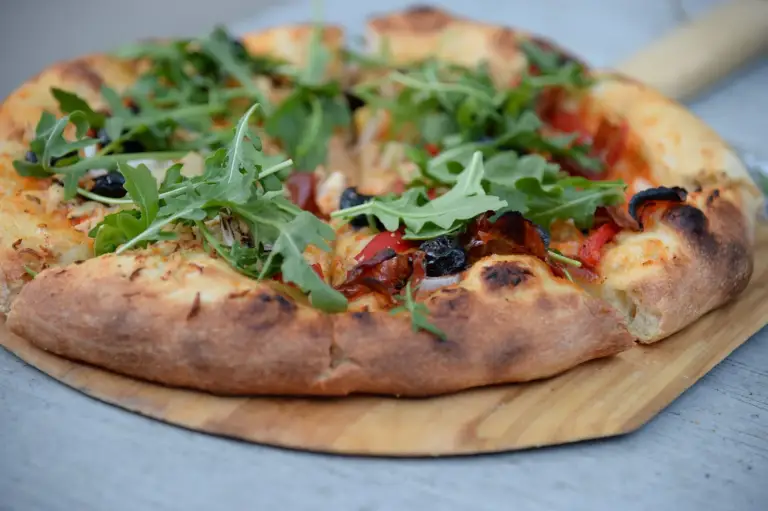 Pizza z rukolą na drewnianym stole
