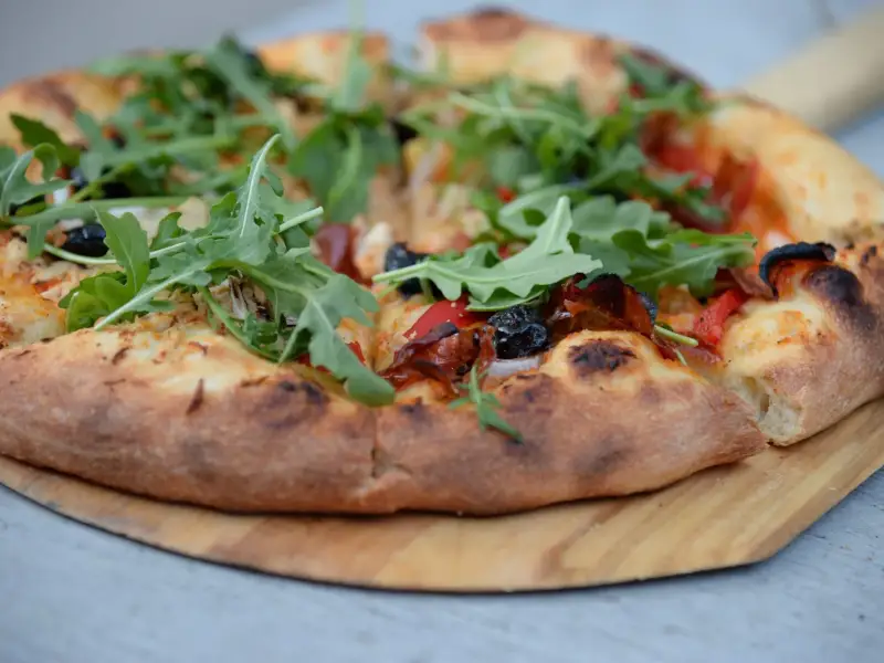 Pizza z rukolą na drewnianym stole