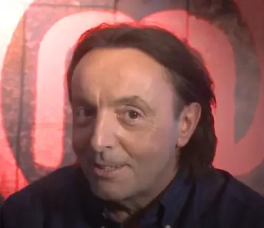 Michel Moran z dłuższymi ciemnymi włosami uśmiecha się do kamery podczas nagrania świątecznego wideo w 2020 roku
